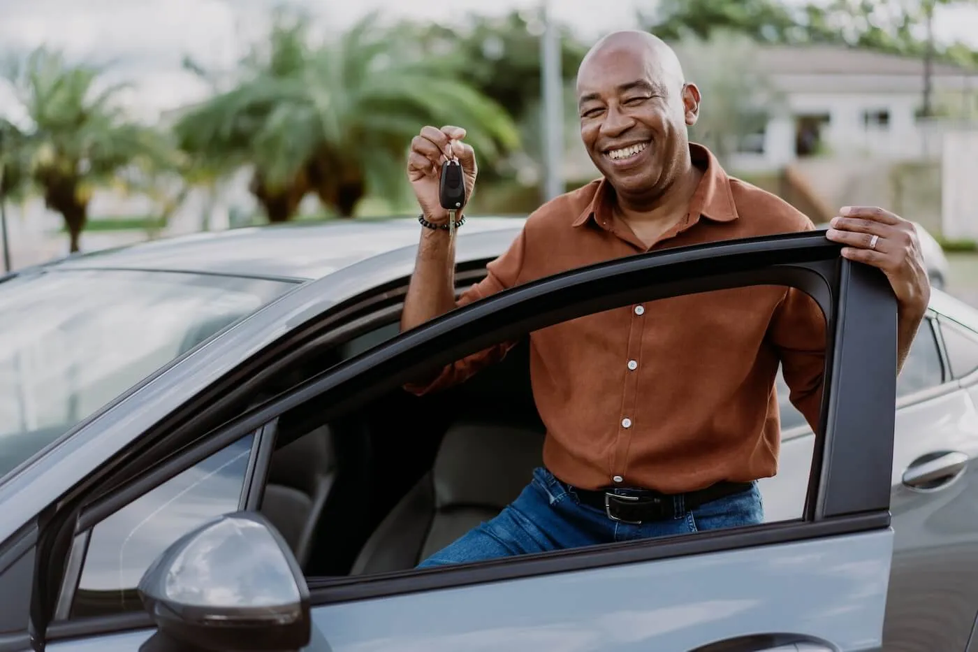 Smiling mature man standing next to his car and holding the car keys