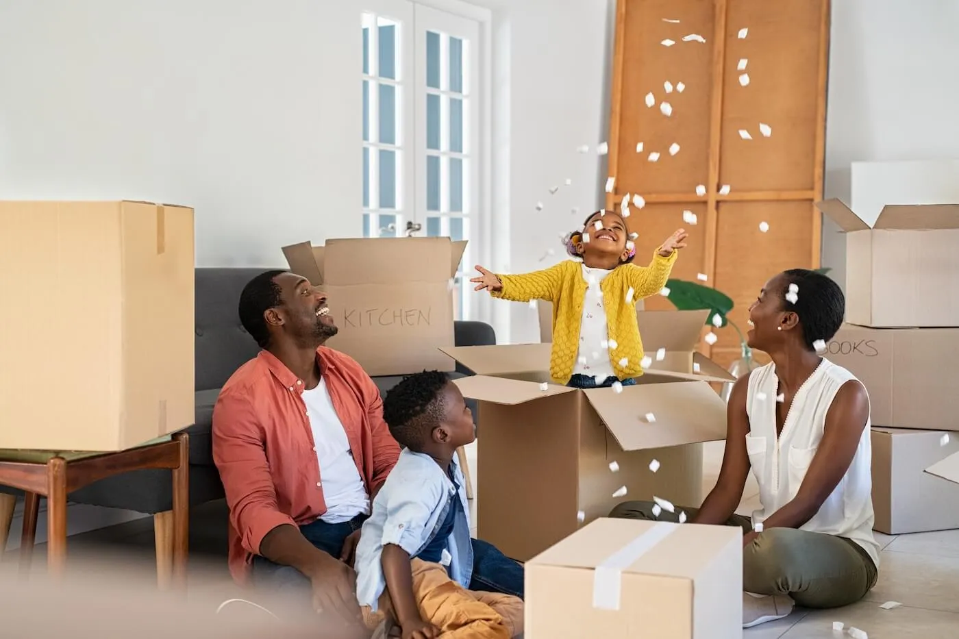 Happy family of four having fun while unpacking the boxes in a new house