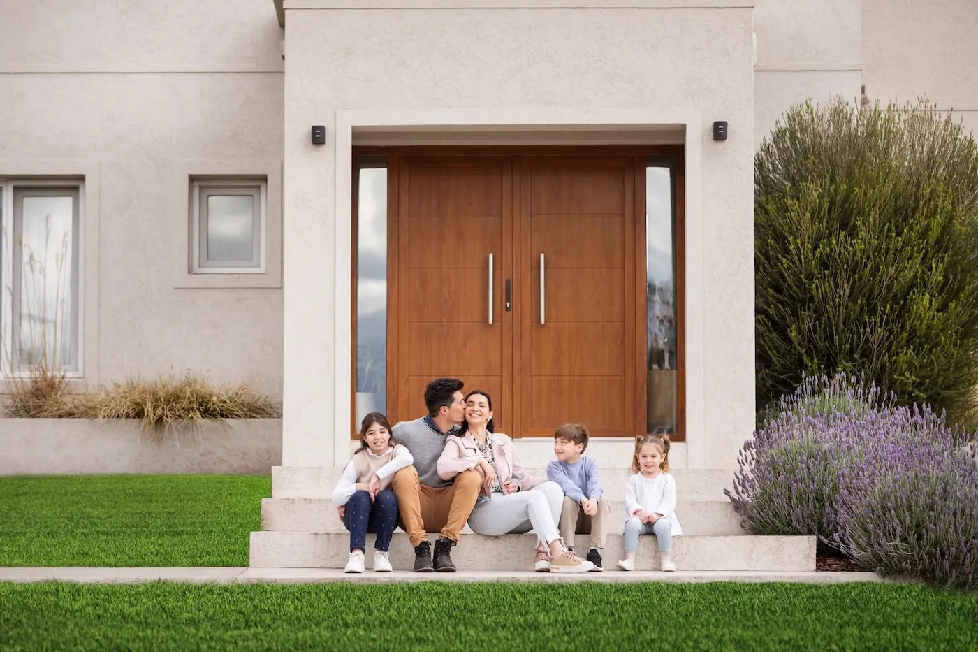 Happy family with three young kids are sitting on the porch of their new house