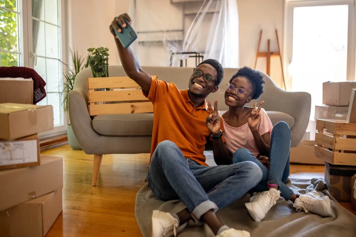 Happy young couple sitting on the floor in their new living room and making a selfie