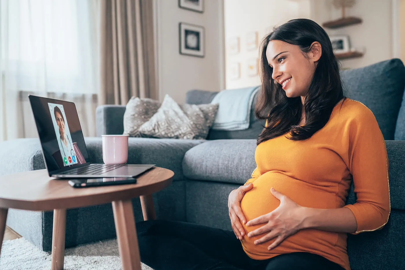 Pregnant woman having video call with doctor at home