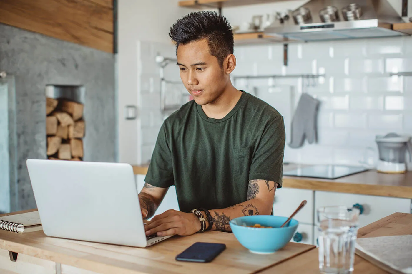 Focused young man using his laptop in the kitchen