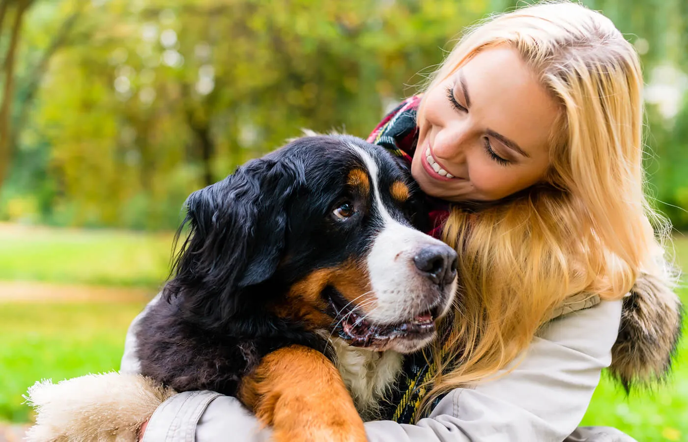 Smiling young woman hugging a large dog outdoors