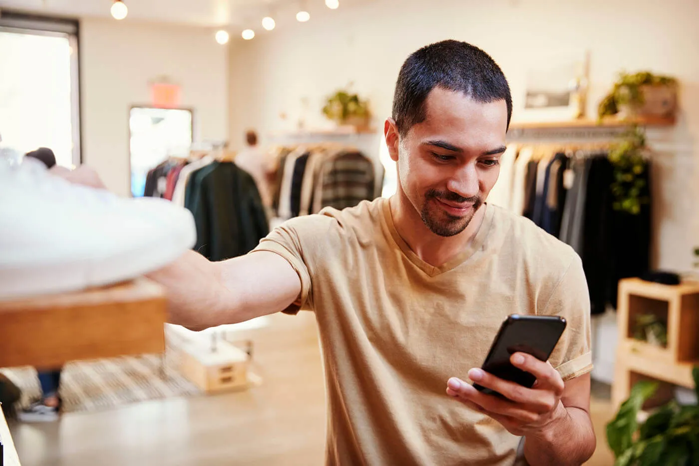 Smiling man checking his smartphone while shopping in a department store