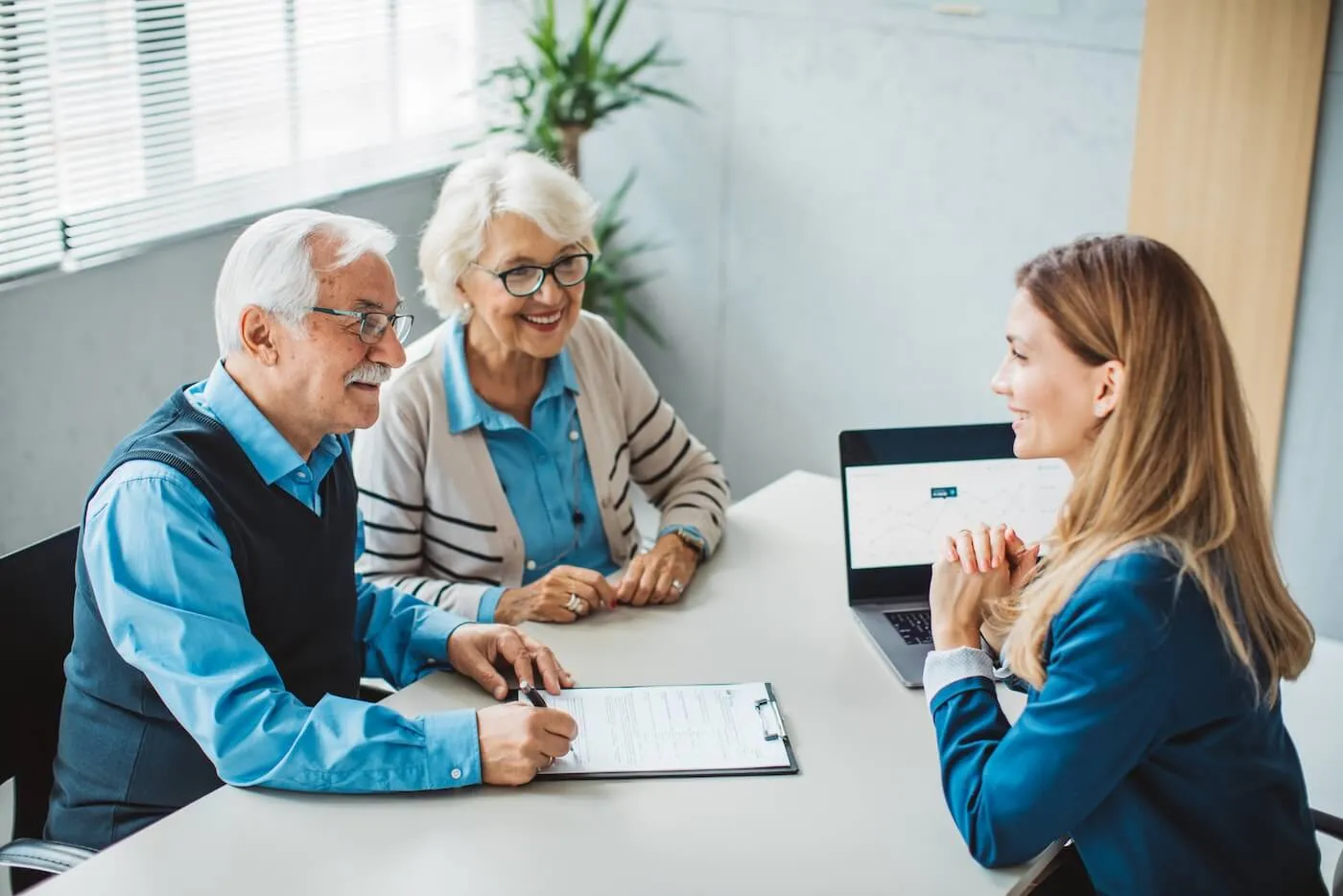 Female bank clerk assisting a senior couple with opening a certificate of deposit (CD) account in a bank office setting