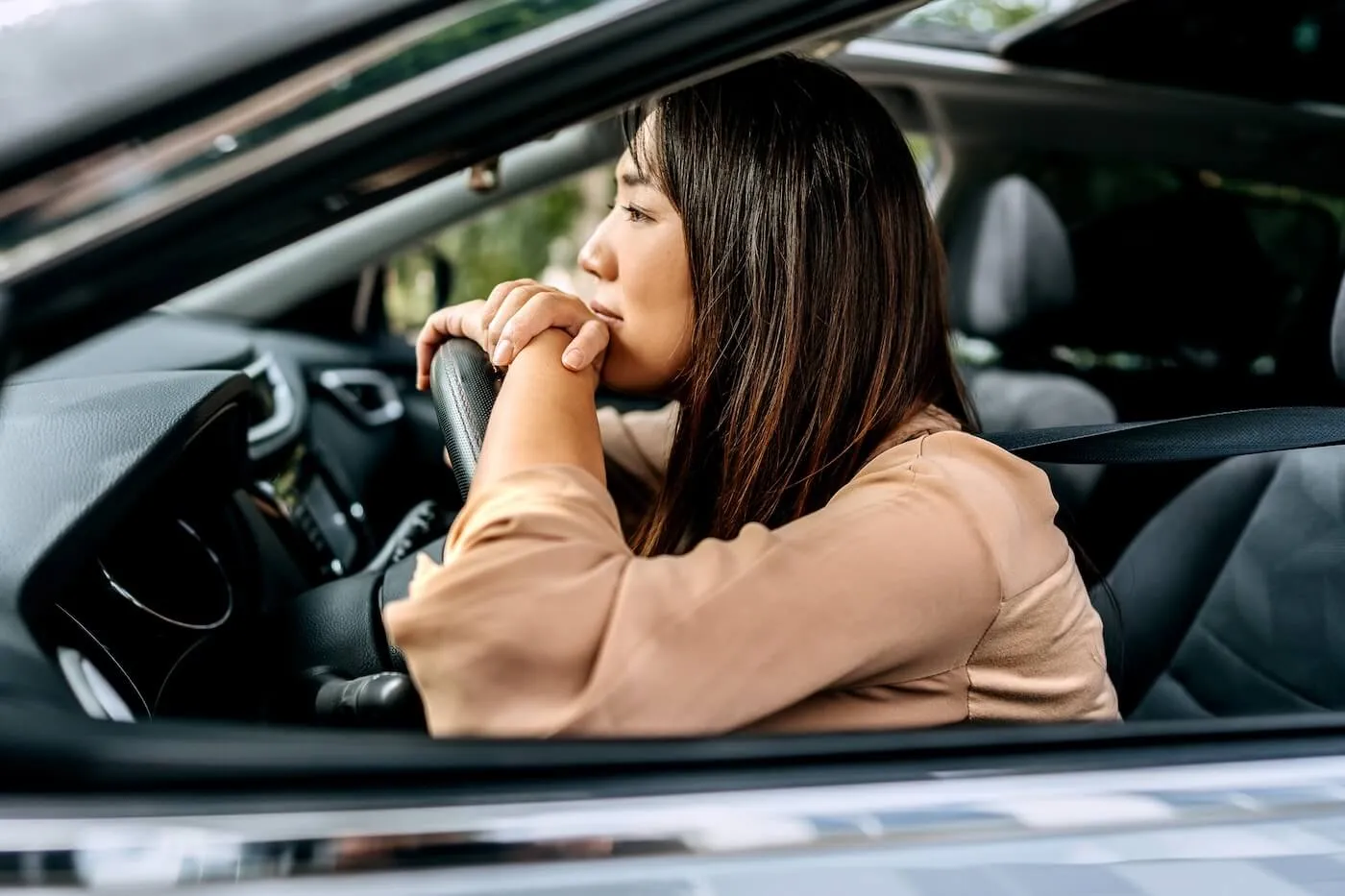 Pensive young woman leaning towards the steering wheel