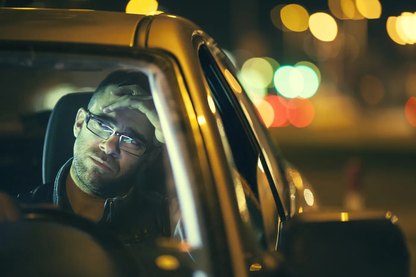 Bankrupt man in his car, wondering if he can keep his car lease or not.