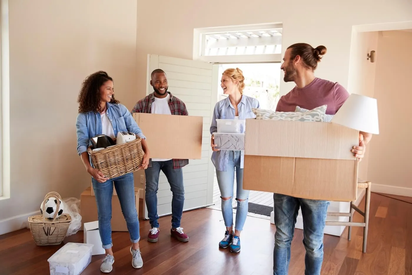 Group of friends, both male and female, entering the house with the moving boxes