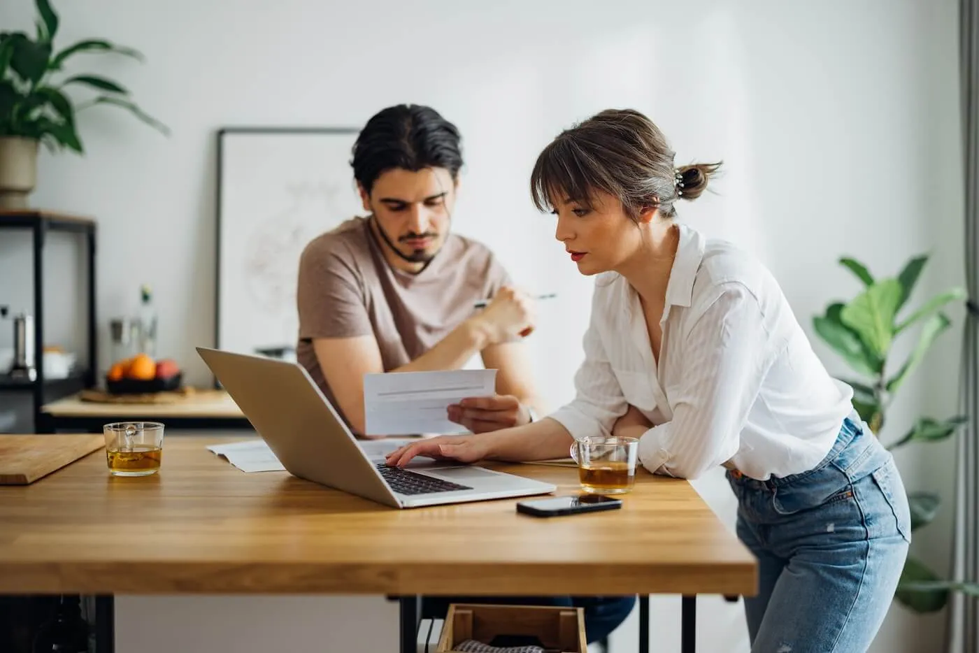 Focused couple planning their finances at home while enjoying hot tea