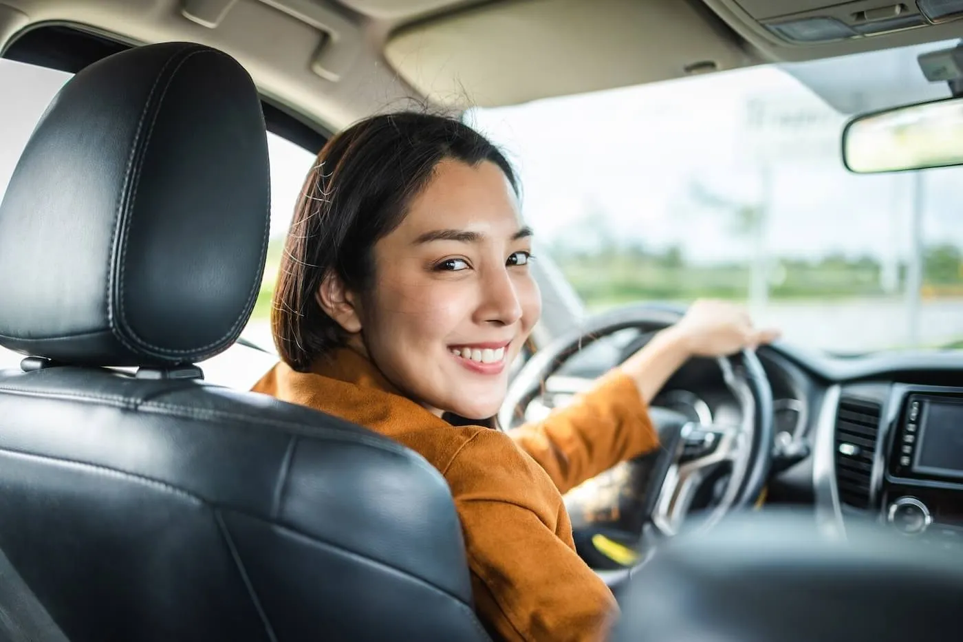 Smiling young woman looks back from the driver's seat