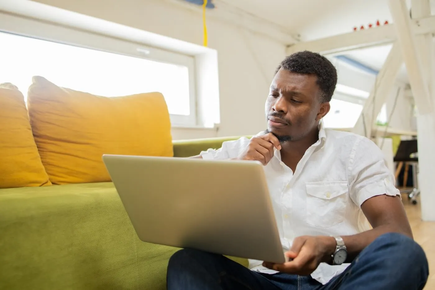 Focused man sitting cozily with a laptop on the floor in the living room