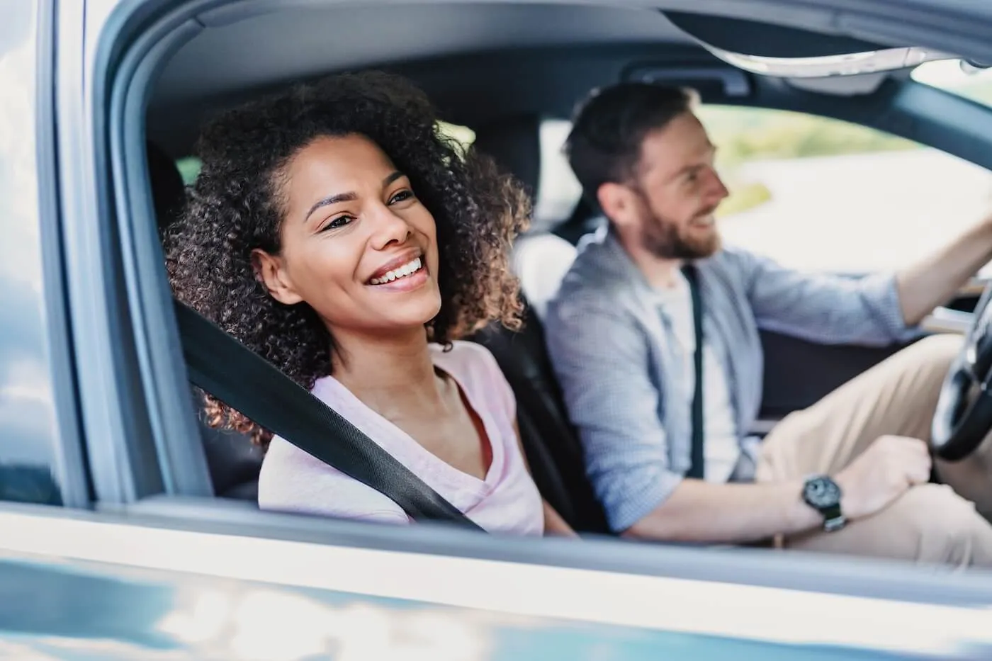 Happy young couple driving a car