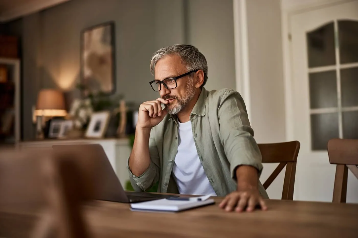 Focused mature man thinking while looking at the laptop screen at home