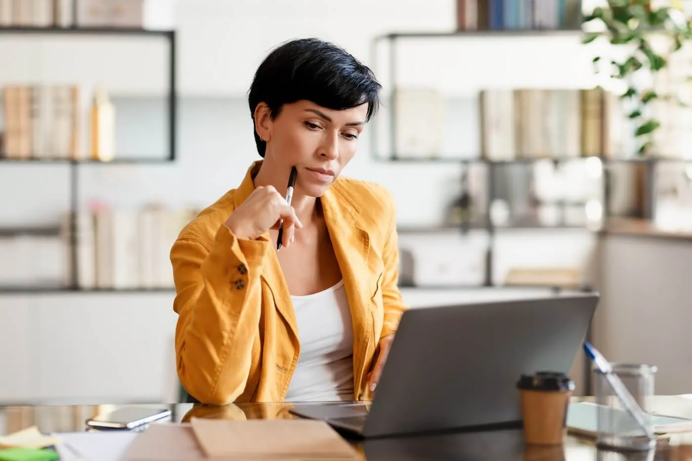 Pensive young businesswoman working on her laptop in the office