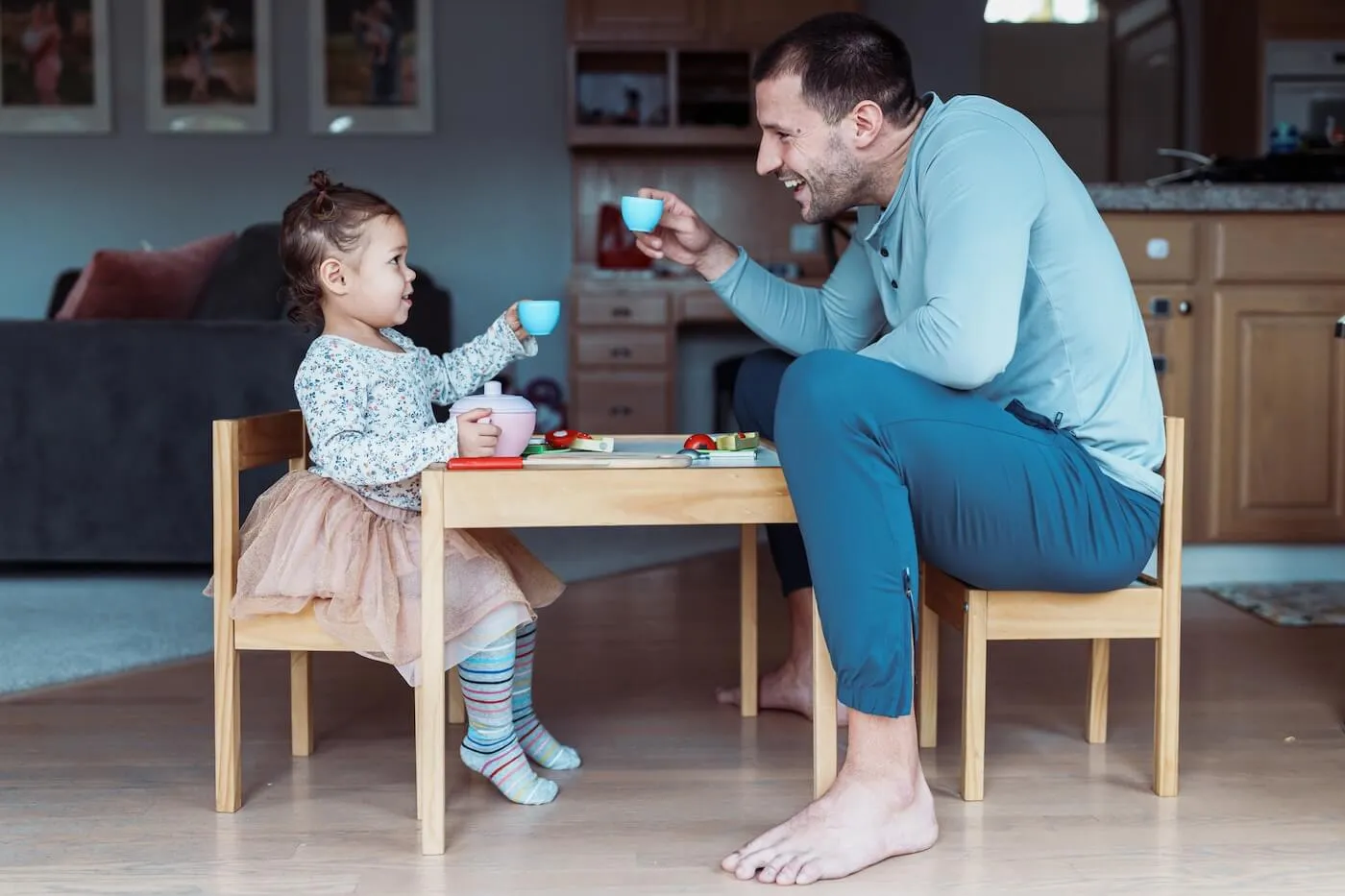 A father and his toddler daughter share a joyful moment during a pretend tea party