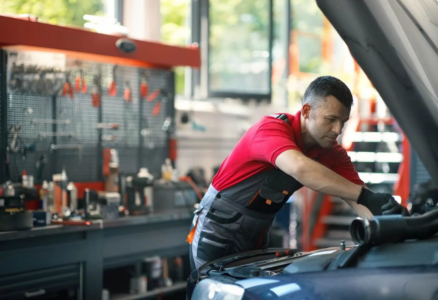 Male technician working under the hood of a car in a body shop