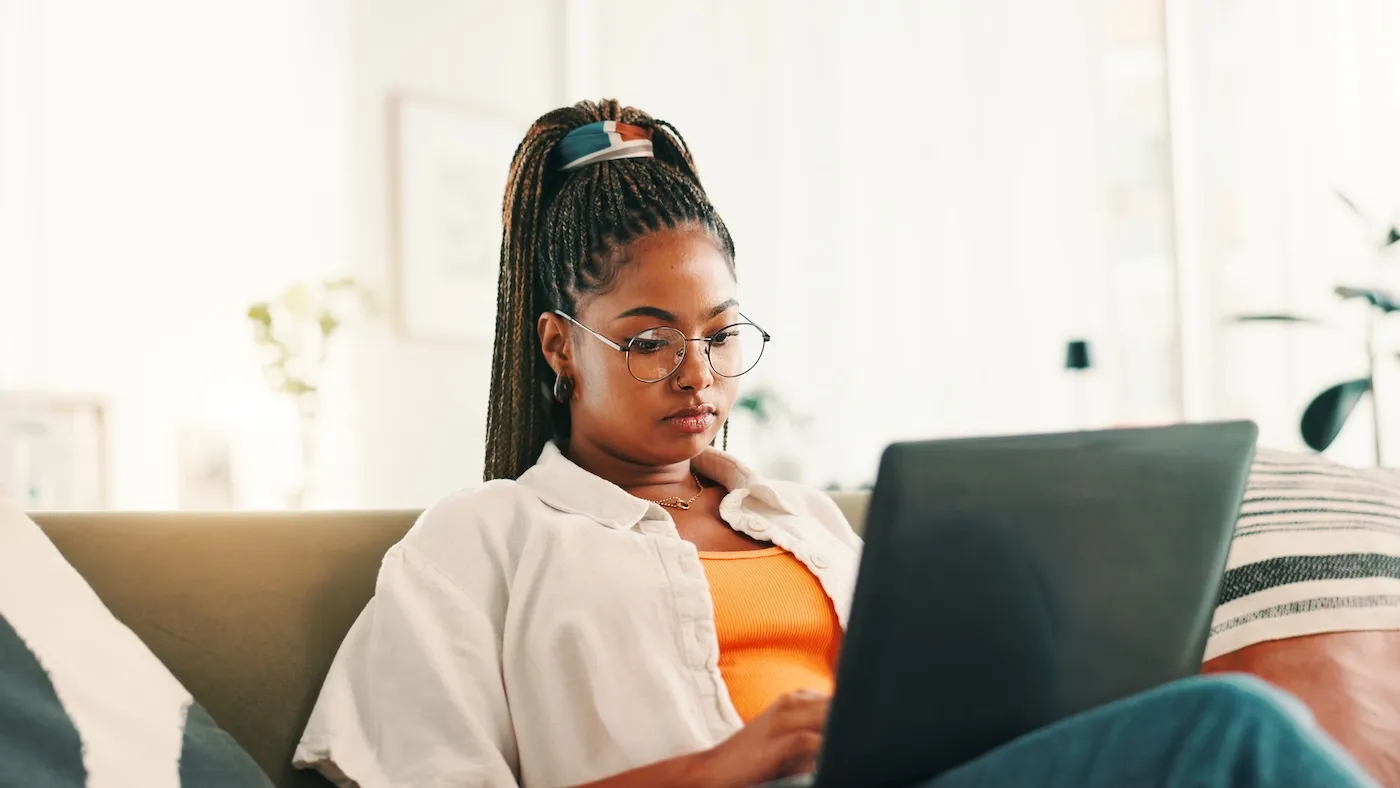 A woman sitting on her couch using her laptop.