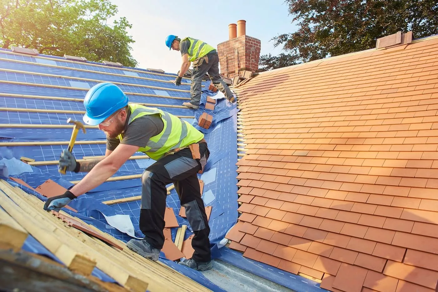 Two male construction workers fixing the house roof on a sunny day