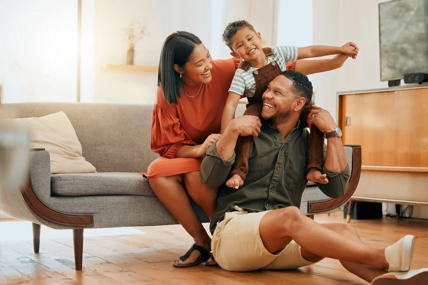 Happy young family with a toddler boy playing in the living room