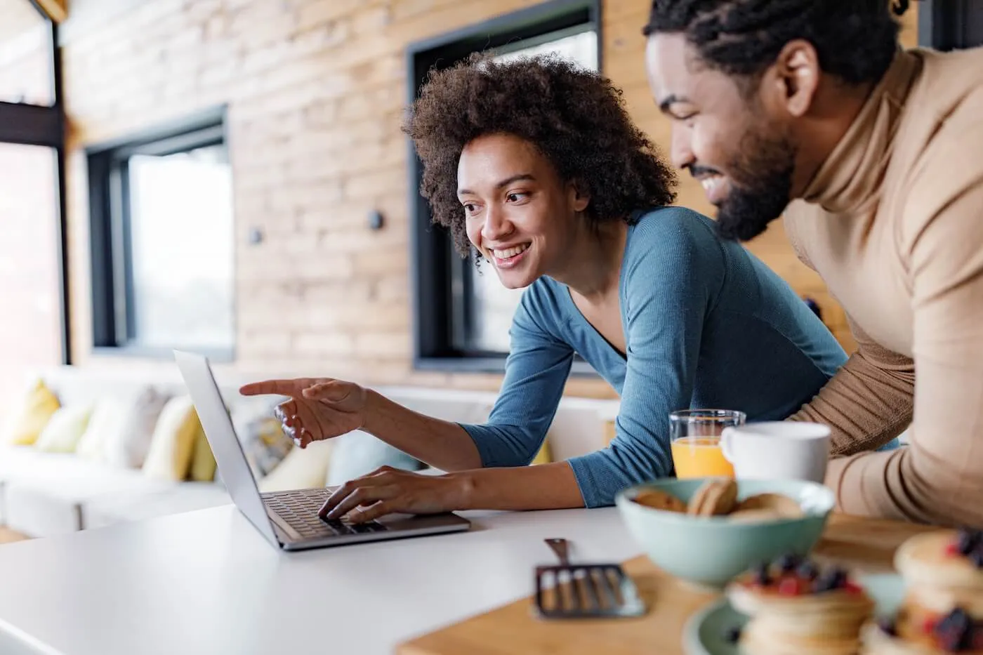 Happy couple using the laptop while cooking in the kitchen