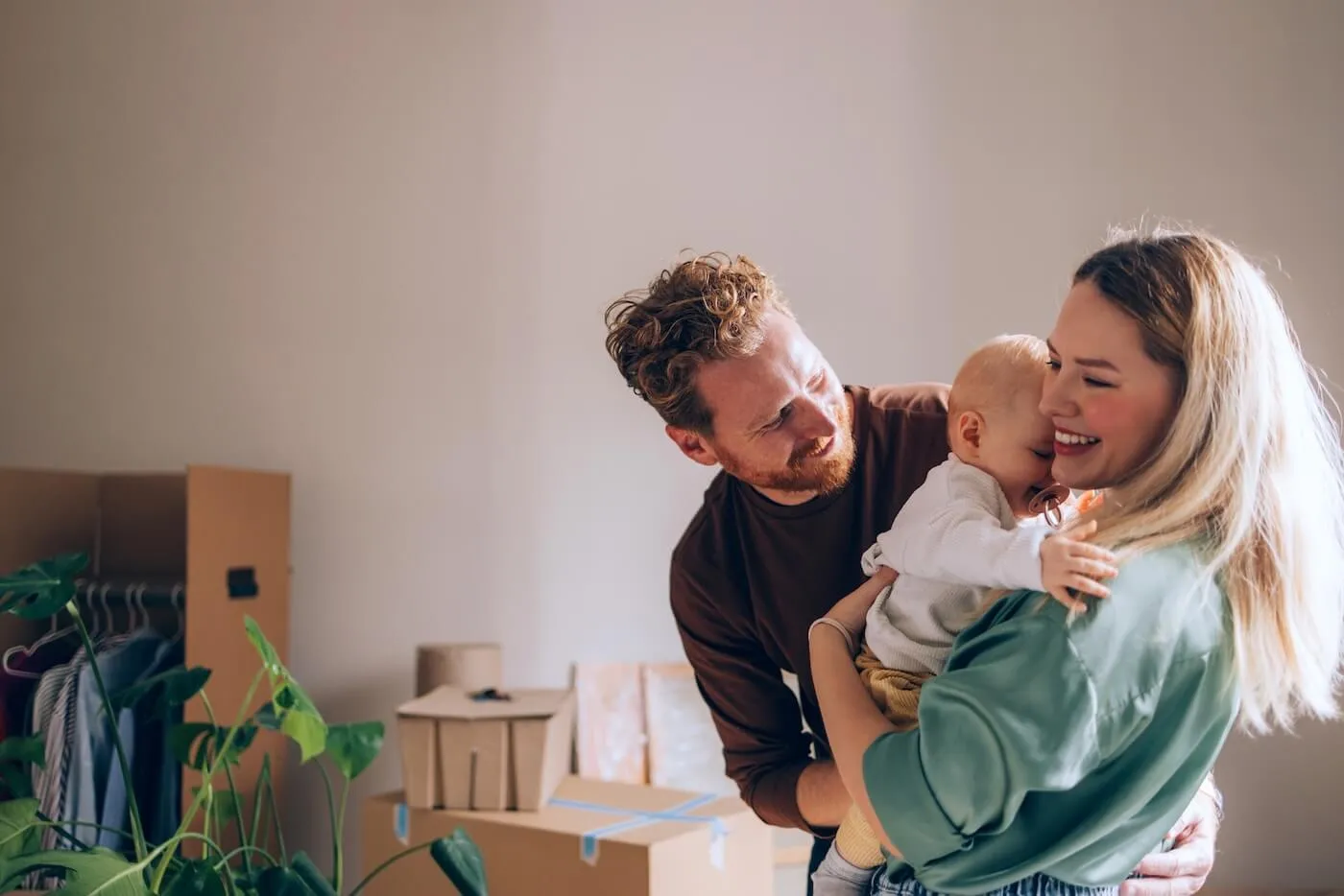 Happy young parents hugging their baby in the new home