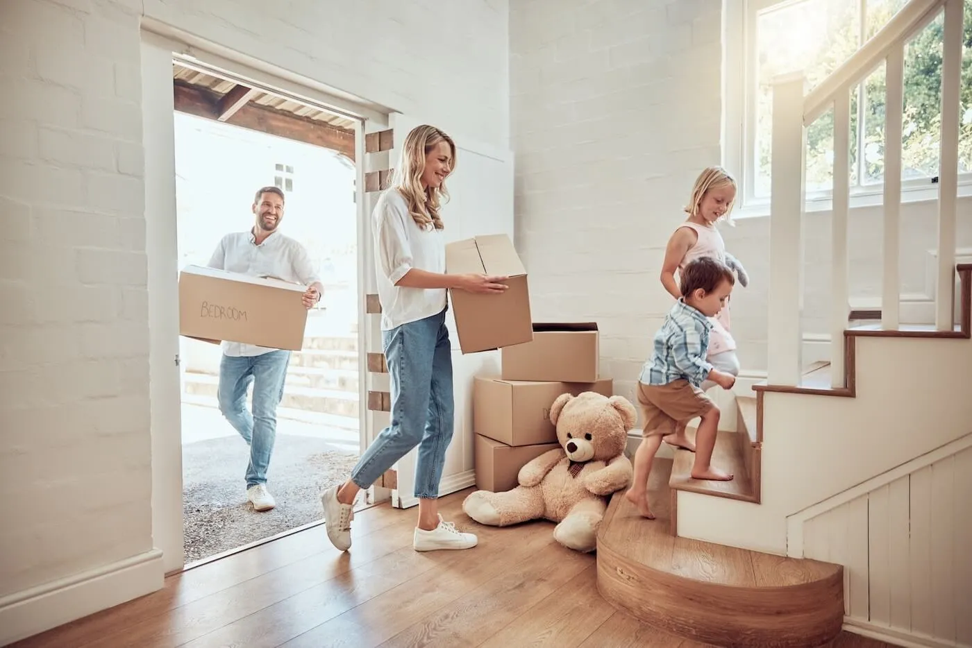 Happy family of four moving boxes into their new home