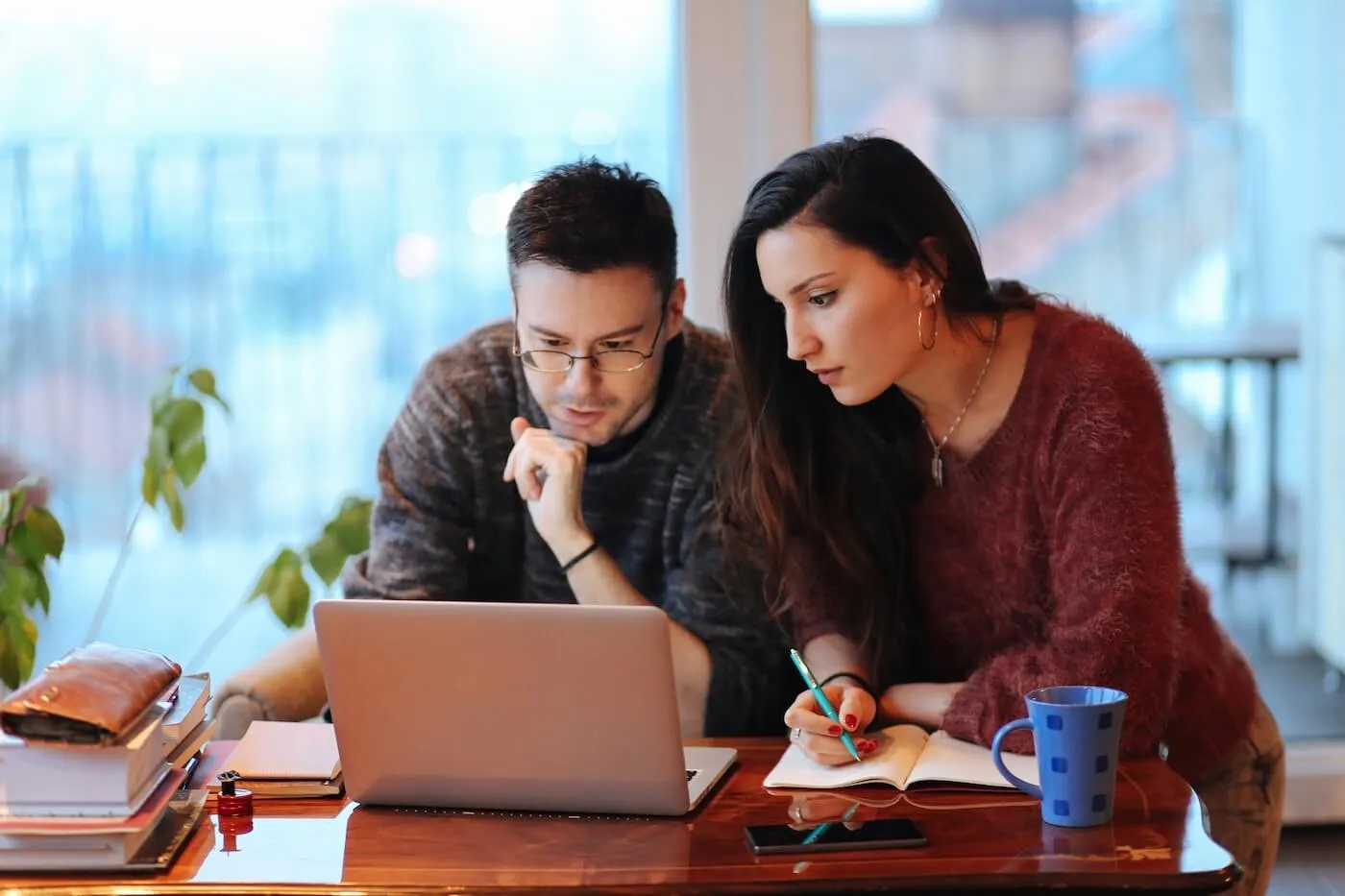 Focused young couple using a laptop and taking notes