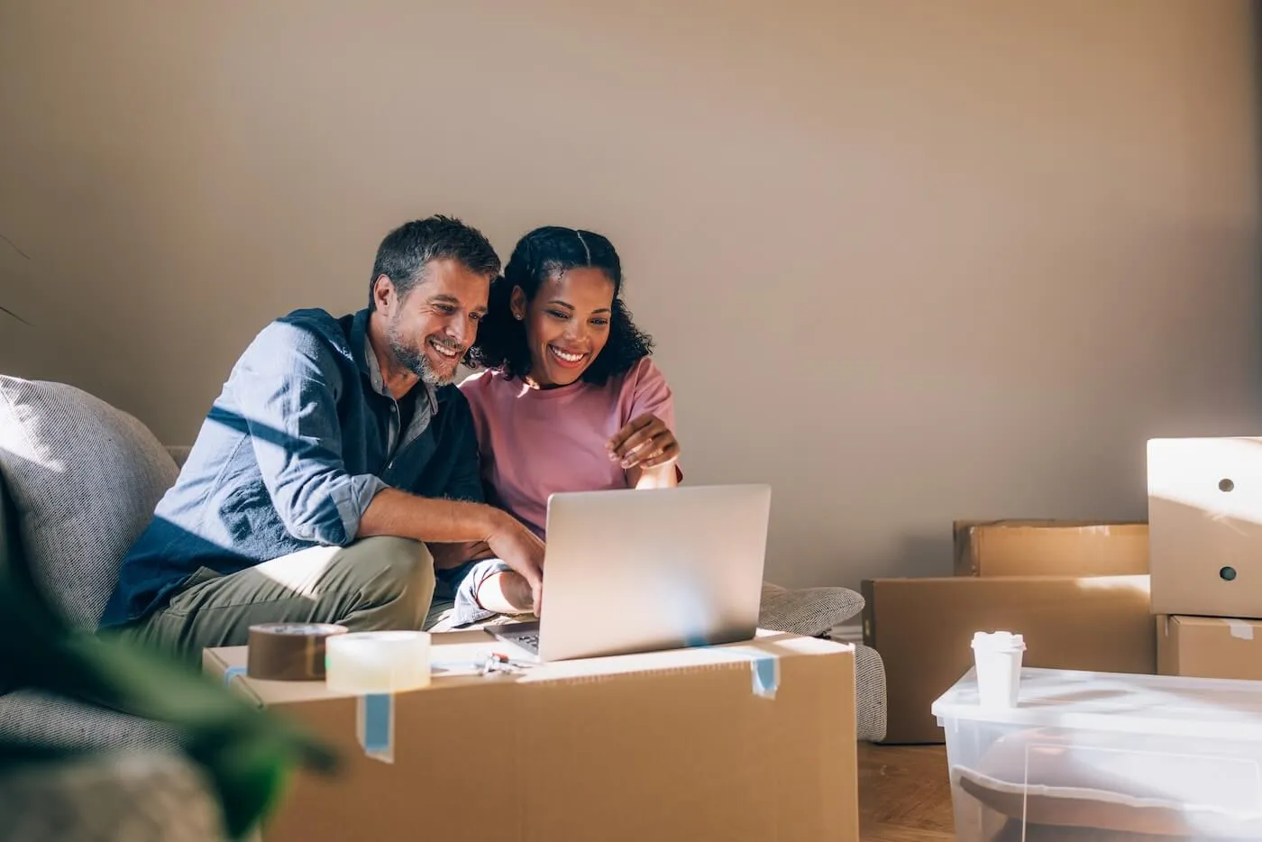 Happy couple using their laptop while moving in