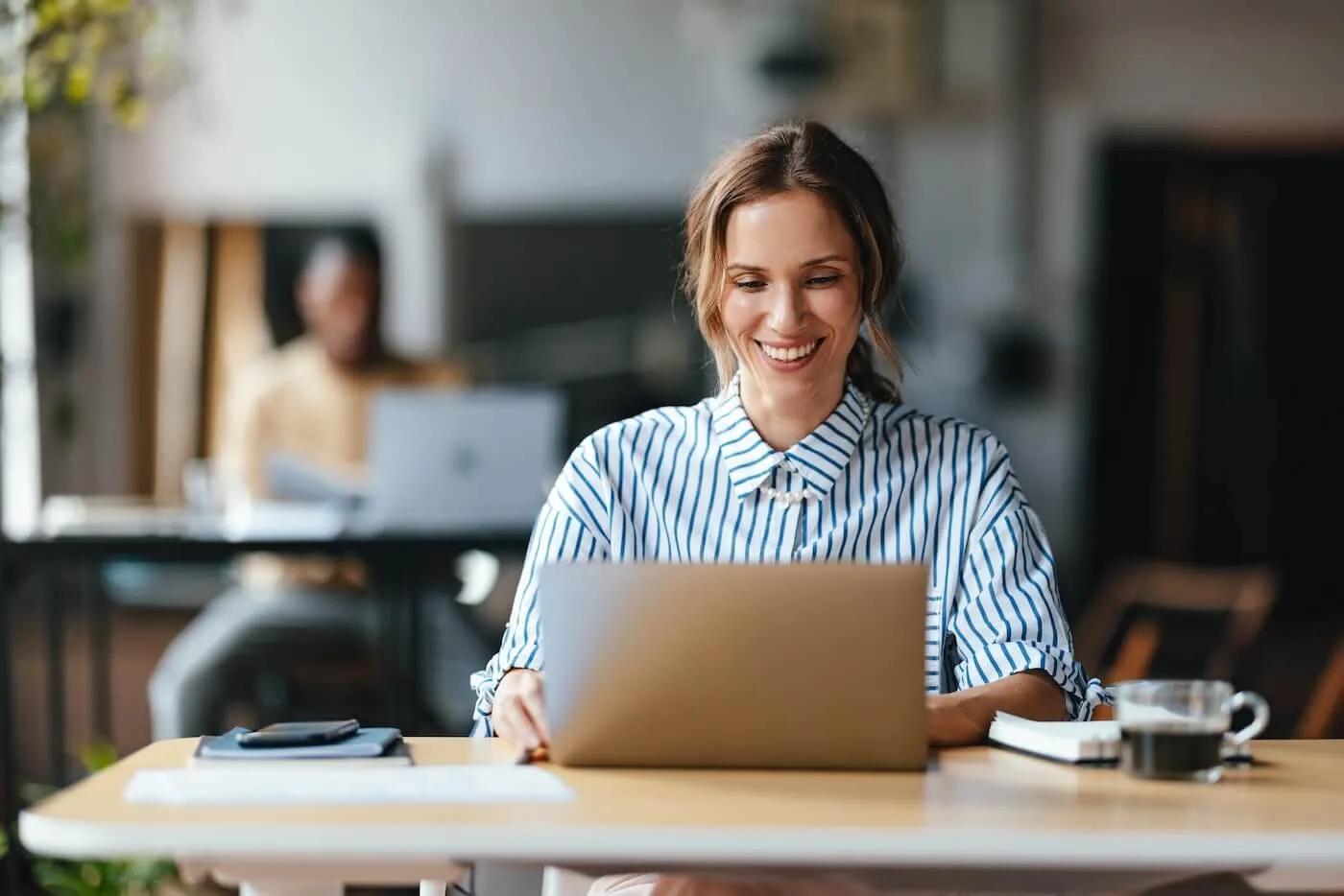 Smiling businesswoman working on her laptop in the office