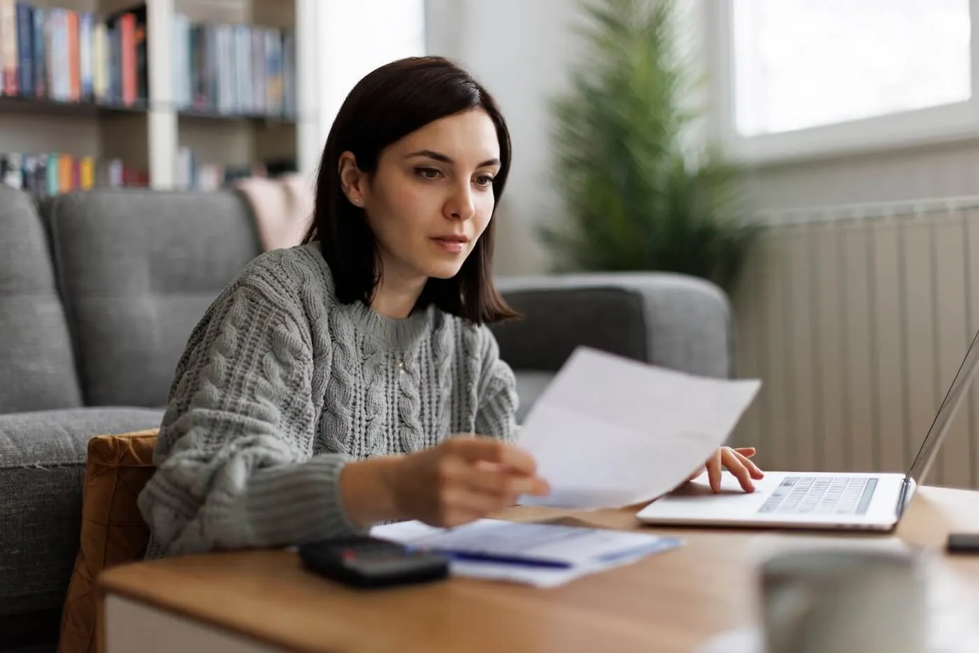 Focused young woman filing taxes online at home