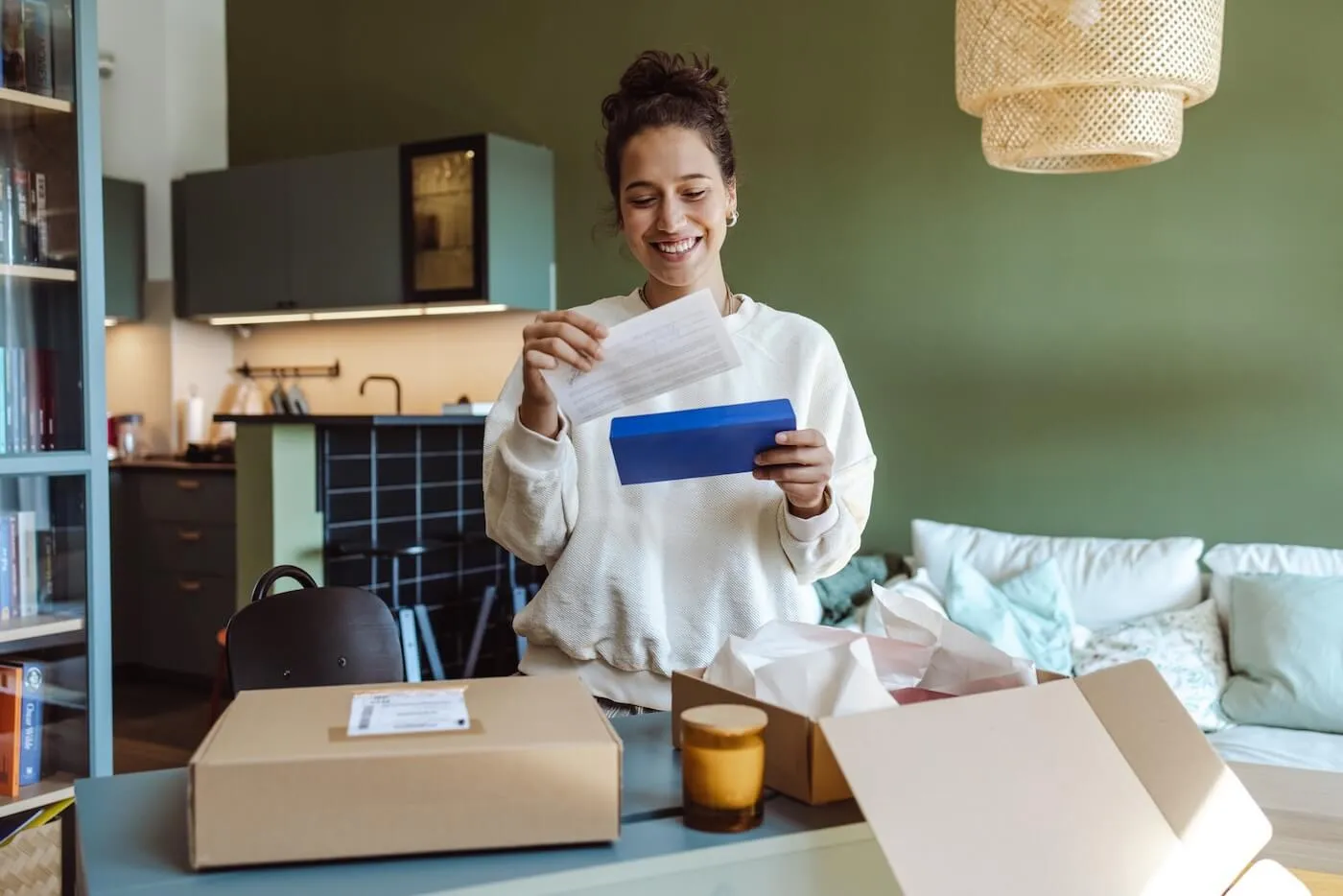 Smiling young woman opens a letter at home