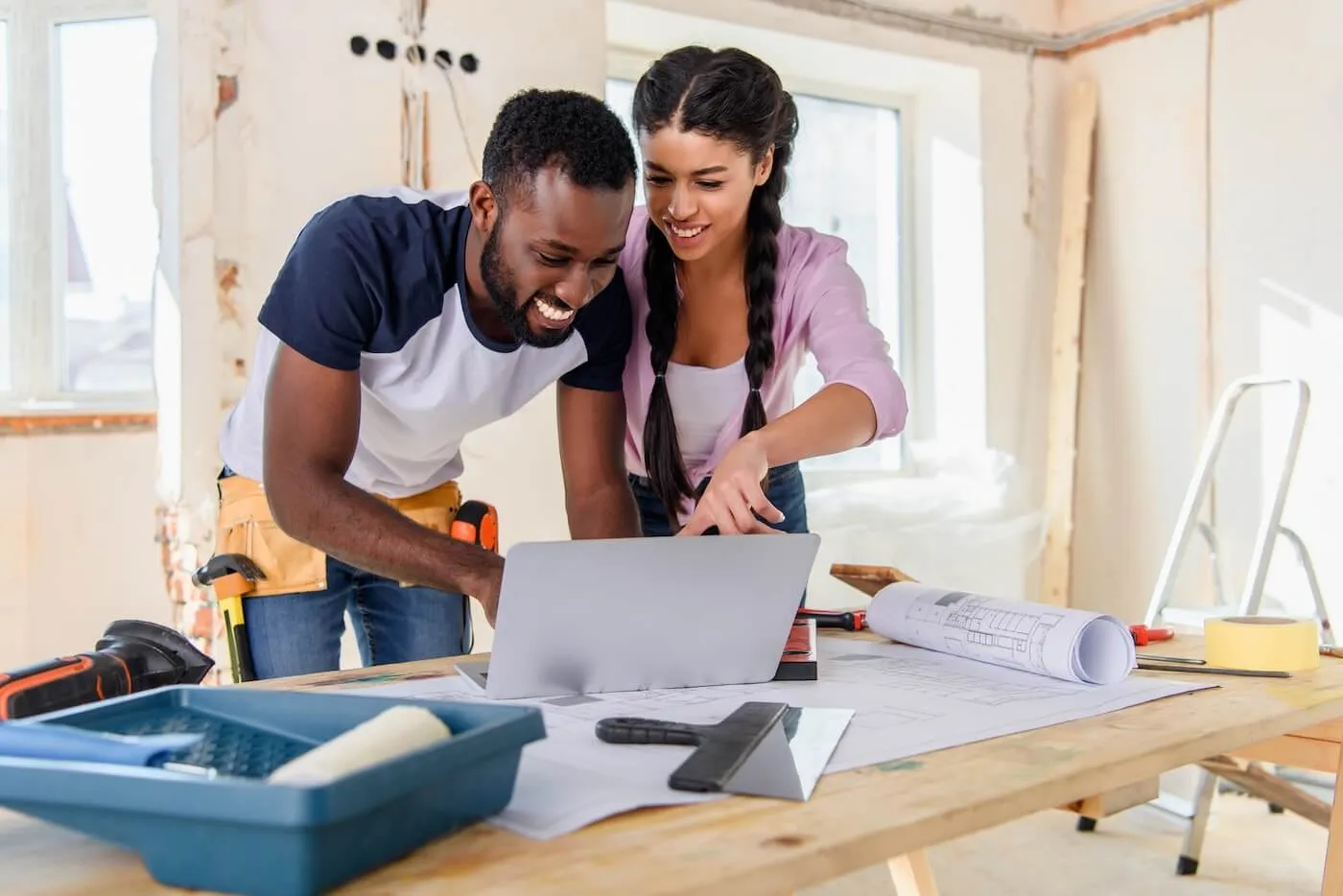 Happy couple suing laptop during home renovation