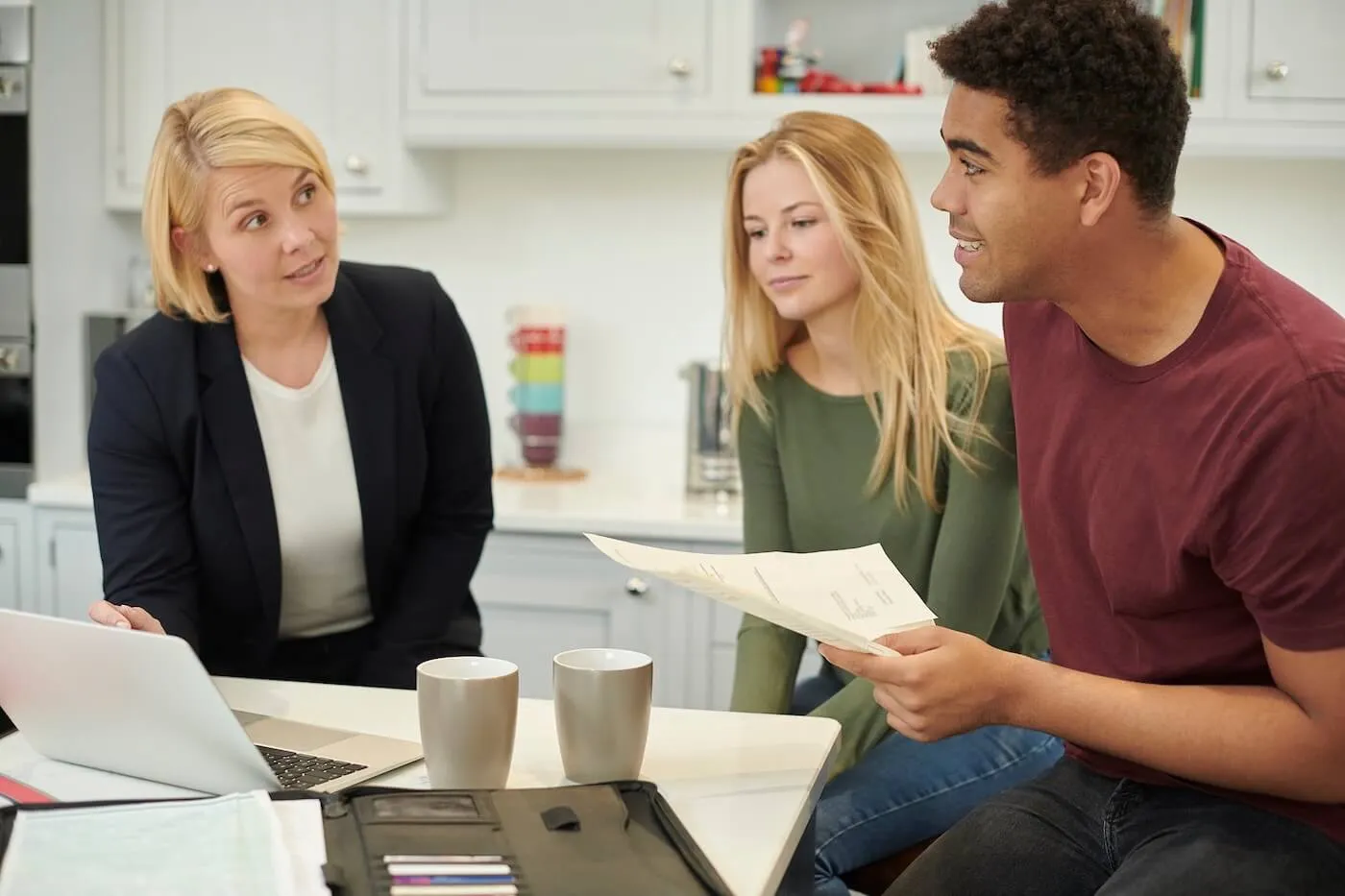 Young couple having a meeting with a female financial adviser at home