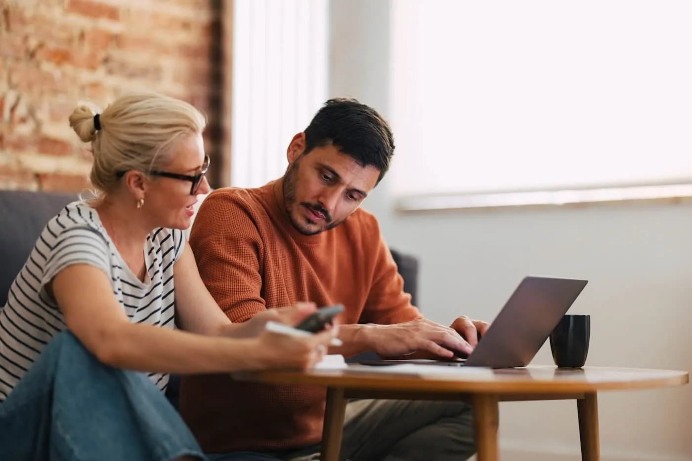 Photo of a mature couple discussing finances at home while using a laptop.