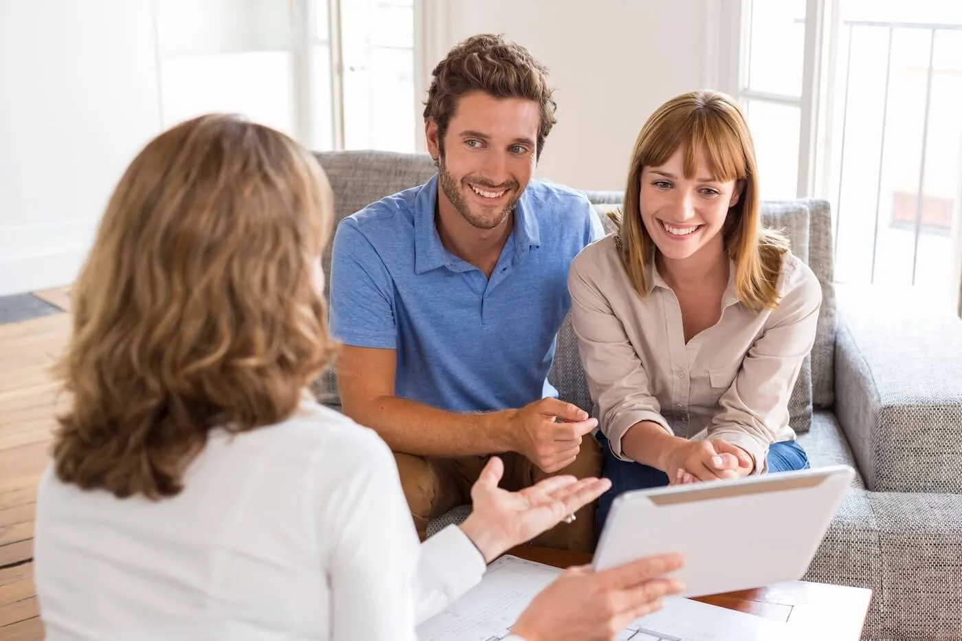 Happy young couple discussing their loan options with a female agent