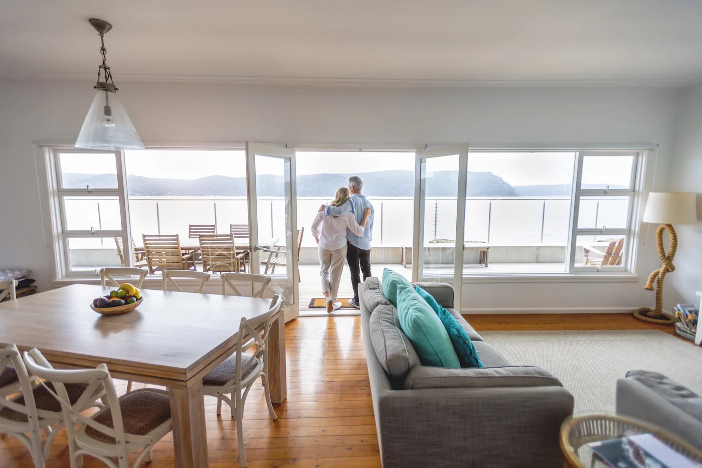 Mature couple looking at the view in their waterfront home. The ocean can be seen in the background.