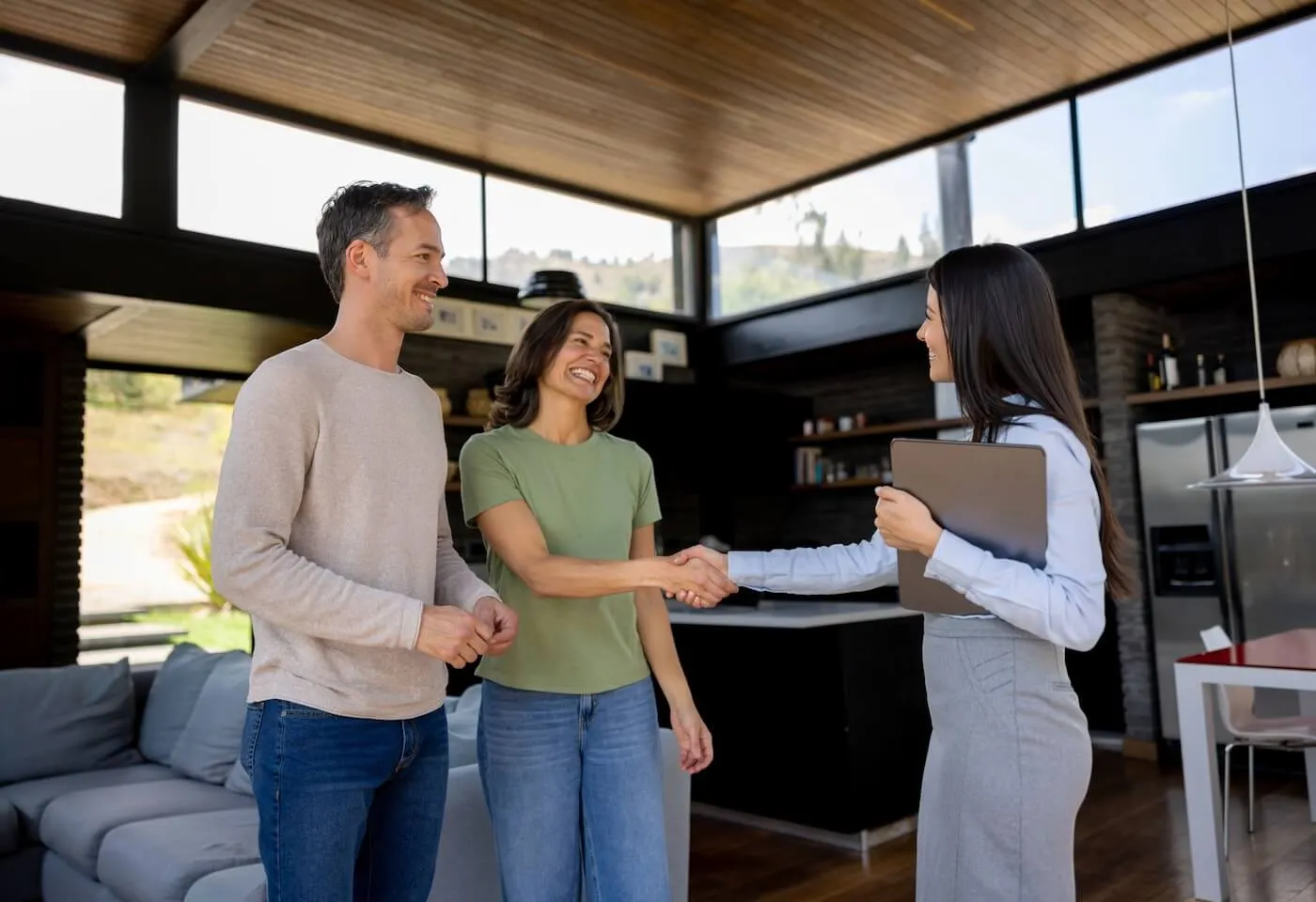 Smiling couple shaking hands with the female agent during the open house