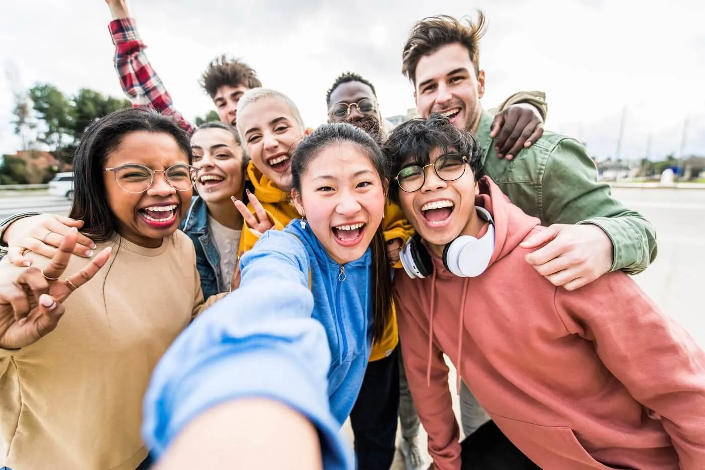 A cheerful group of diverse students taking a selfie outside