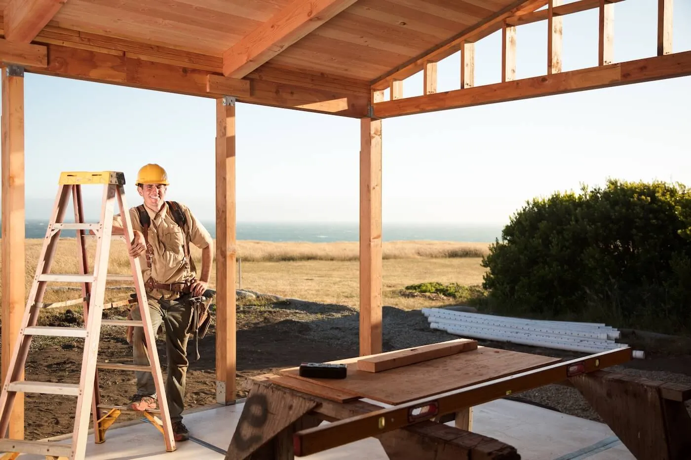 Smiling construction worker leaning toward the site leader at a construction area with a scenic sea view in the background