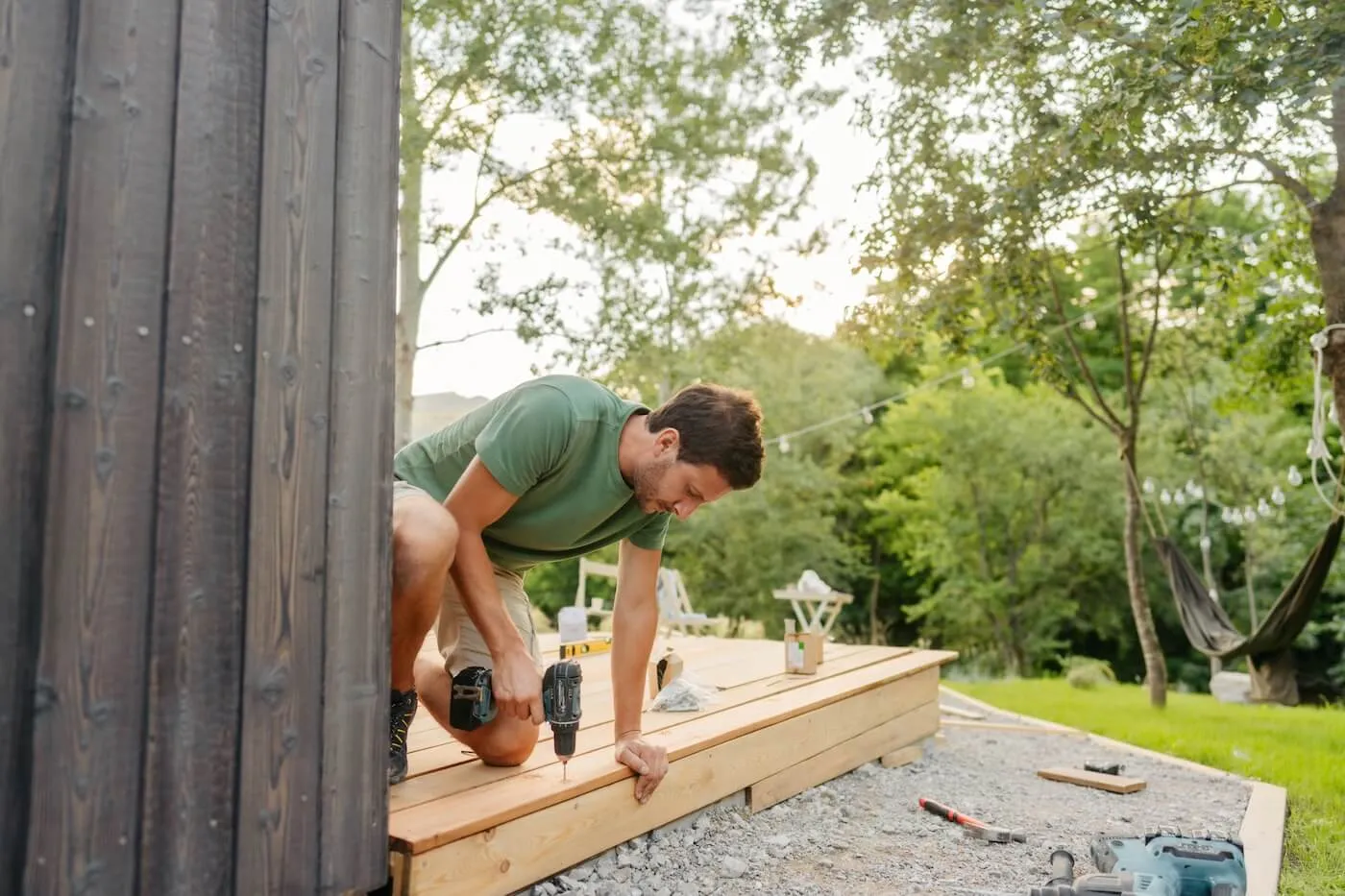 Young man building a house deck in summer