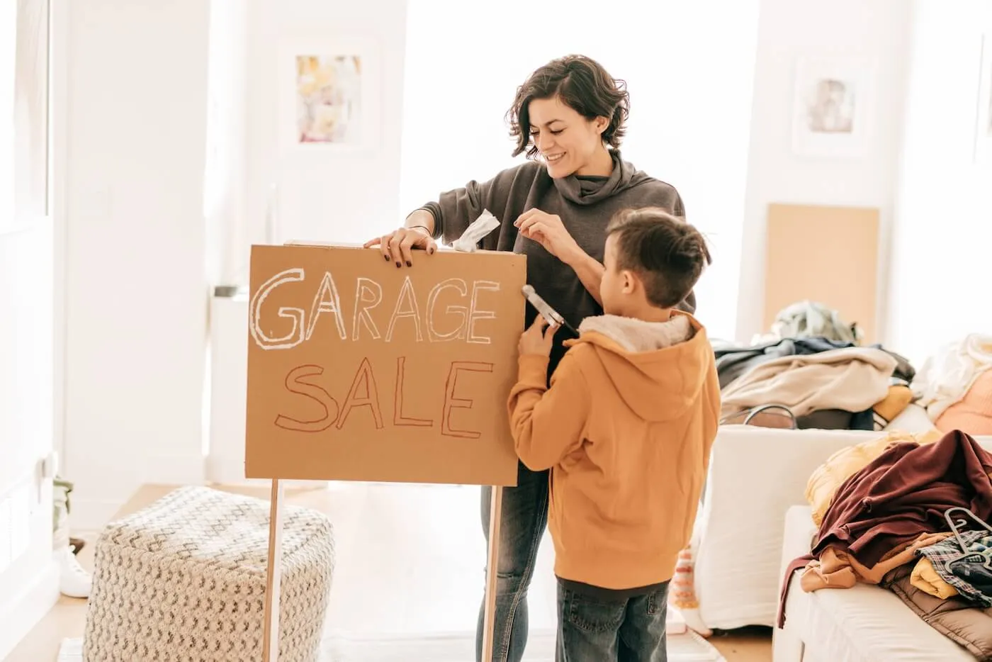 Mother and son preparing a sign for a garage sale at home.
