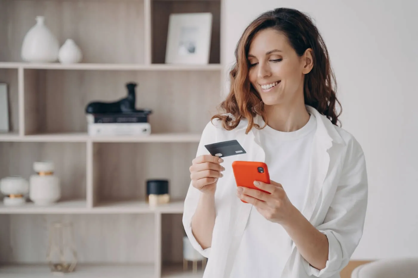 Smiling woman paying her credit card bill via mobil app at home