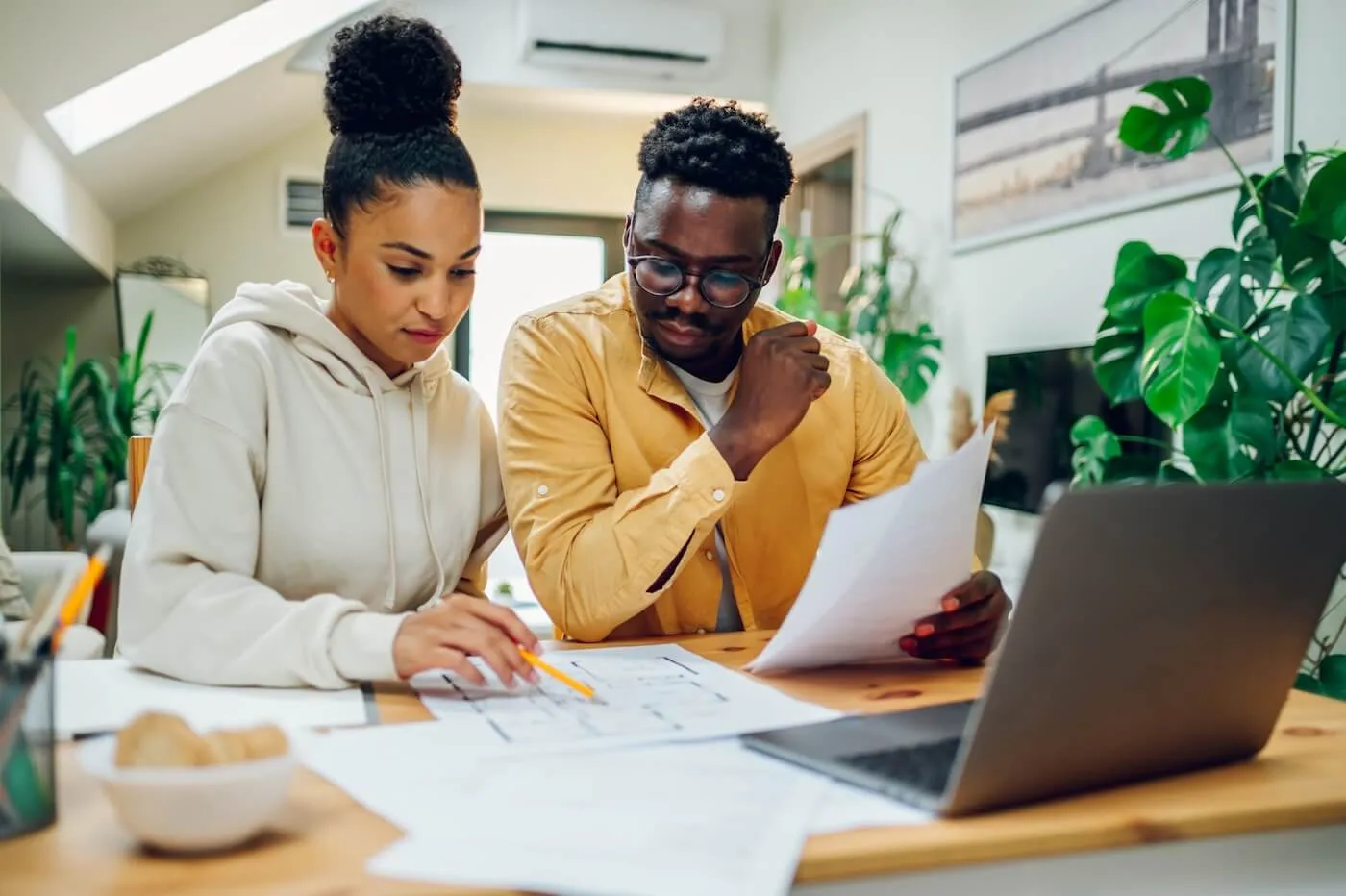 Focused young couple planning their budget at home with a laptop beside them