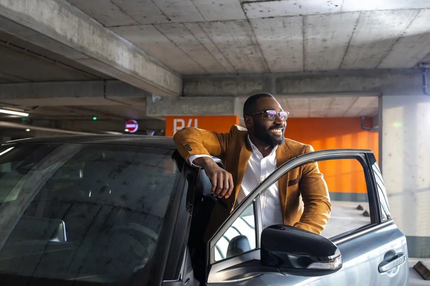 Smiling man gets out of the car on a covered parking lot