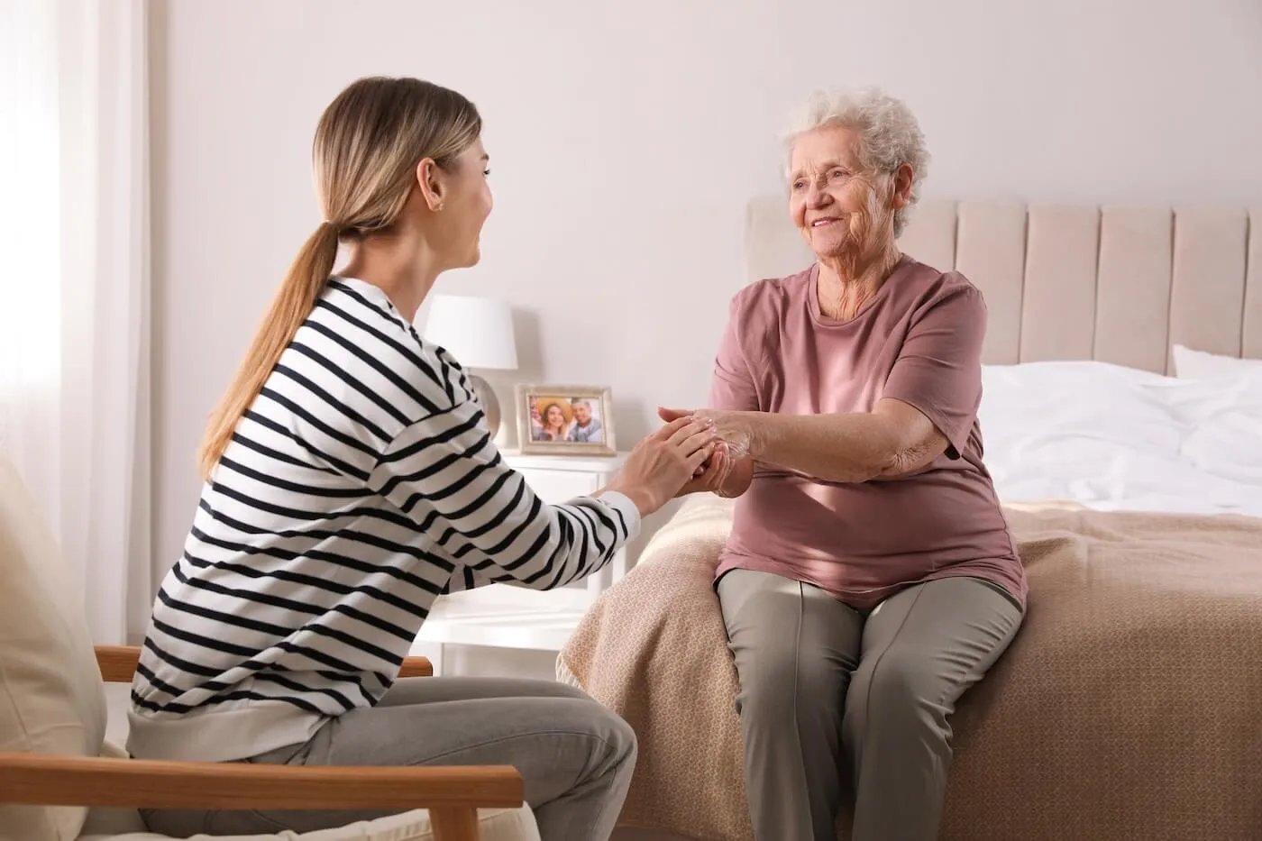 An adult daughter visiting her elderly mother in an aged care facility.