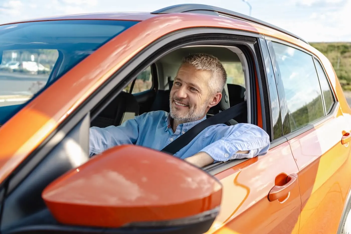 Smiling mature man driving an orange car