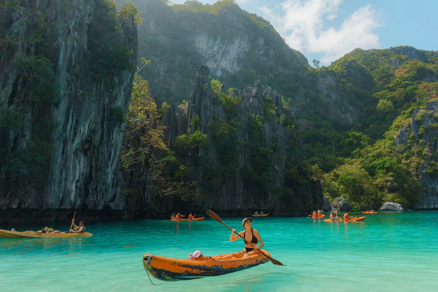 Carefree woman kayaking on El Nido during island-hopping experiential trip to Philippines.