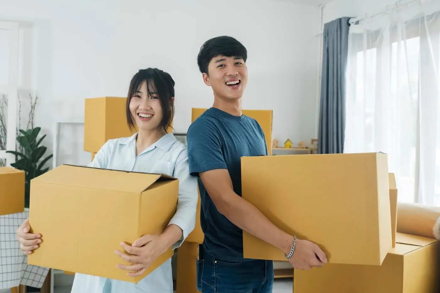 Happy young couple holding the moving boxes in their new living room