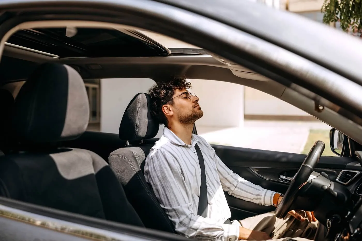Tired young man sitting in the car with eyes closed