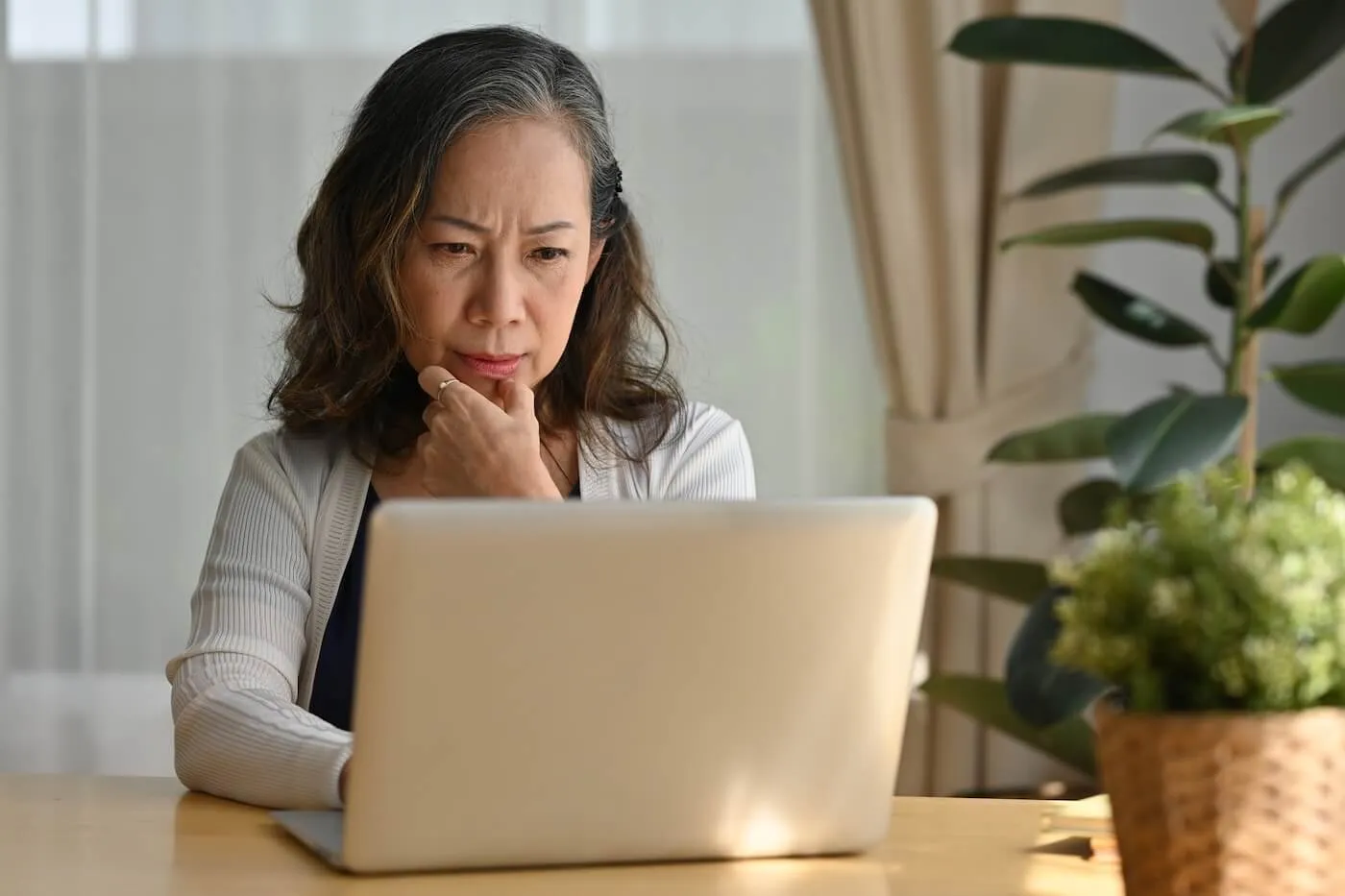 Concerned mature woman using her laptop at home